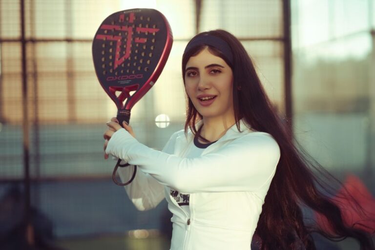 Een speler die een padelracket met middenbalans vasthoudt op de baan, klaar om te slaan.