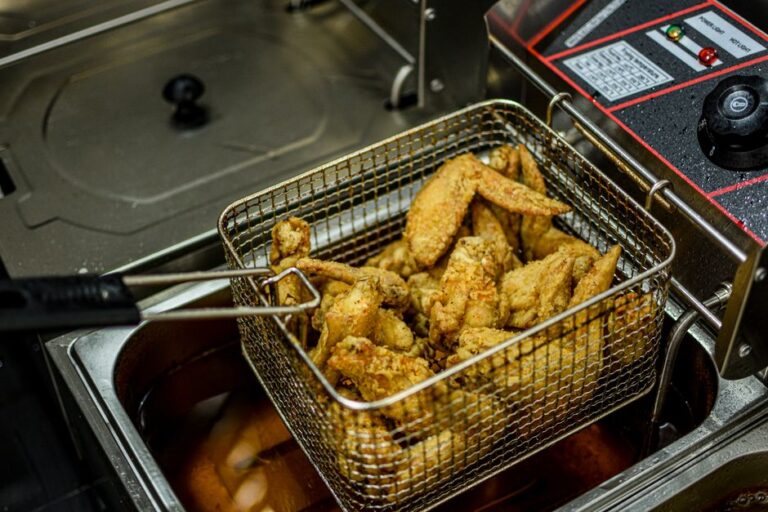 Een professionele friteuse in een drukke horecakeuken met knapperige friet en snacks.