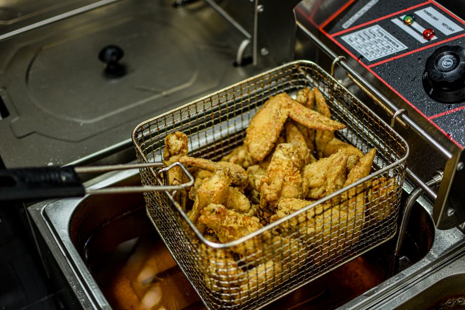Een professionele friteuse in een drukke horecakeuken met knapperige friet en snacks.